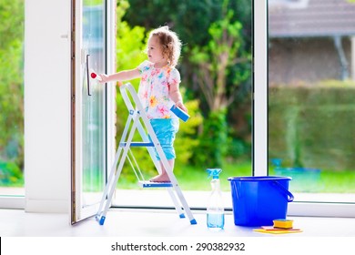 Little Girl Washing A Window. Kids Clean The House. Children Help At Home. Toddler Kid Cleaning Windows And Doors Standing On A Ladder. Child Helping With Housework Holding Sponge And Soap Bottle. 