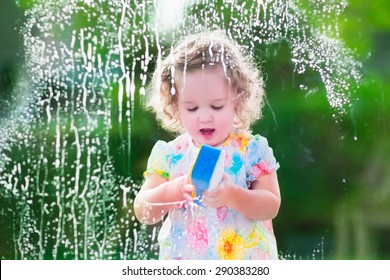 Little Girl Washing A Window. Kids Clean The House. Children Help At Home. Toddler Kid Cleaning Windows And Doors Standing On A Ladder. Child Helping With Housework Holding Sponge And Soap Bottle. 