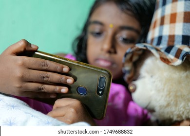 A Little Girl Watching Mobile Phone With Teddy Bear