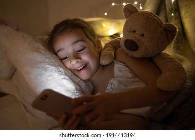 Little Girl Watching Smartphone In Bed, Kid Using Phone And Play Game, Child Using Mobile, Addicted Game And Cartoon.