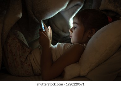 Little Girl Watching Smartphone In Bed, Kid Using Phone And Play Game, Child Using Mobile, Addicted Game And Cartoon.