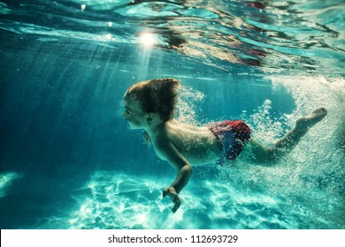 The Little Girl In The Water Park Swimming Underwater And Smiling