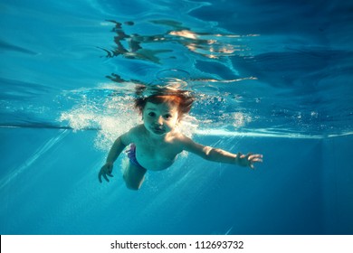 The Little Girl In The Water Park Swimming Underwater And Smiling