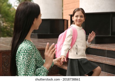 Little Girl Waving Goodbye To Mother Near School Entrance Outdoors