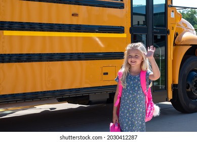 Little Girl Waving As She Waits To Get On School Bus