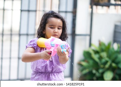 Little girl Wear purple dress playing with plastic water gun
