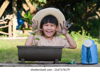 Little girl wearing a hat helps her mother in the garden, a little gardener. Cute girl planting flowers in pots. Cute little girl smiles and shows off her dirty hands in the backyard.