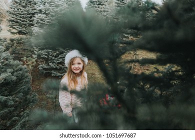 Little Girl Wearing Santa Hat Cutting Down Christmas Tree