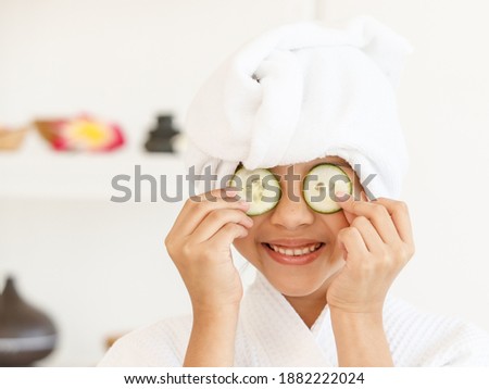 A little girl wearing spa dress playing and teasing together with pieces of cucumber as a treatment object.