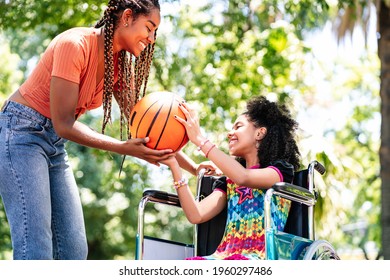 Little Girl In A Wheelchair Playing Basketball With Her Mother.