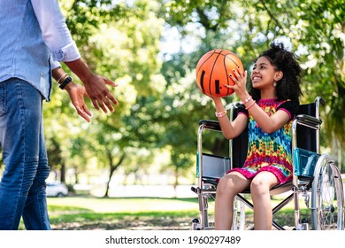 Little Girl In A Wheelchair Playing Basketball With Her Father.