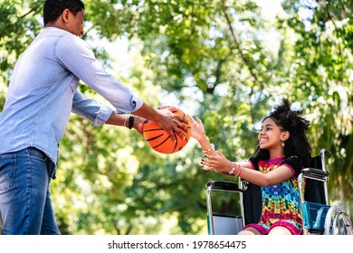 Little Girl In A Wheelchair Playing Basketball With Her Father.