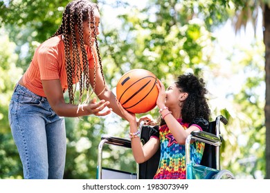 Little Girl In A Wheelchair Playing Basketball With Her Mother.