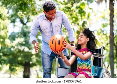 Little Girl In A Wheelchair Playing Basketball With Her Father.