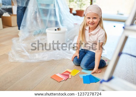 Little girl while painting in new house with wall paint to choose from