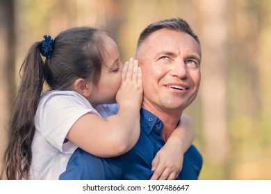 Little girl whispering in father ear, family trust concept