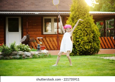 Little Girl In White Dress Playing Badminton In The Garden