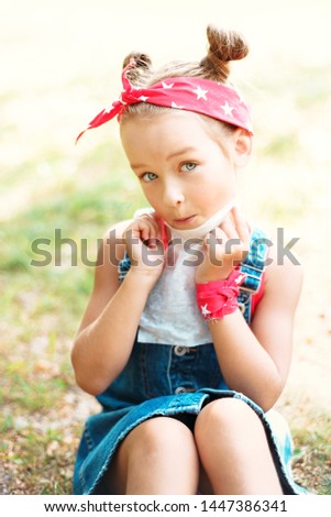 Little girl wipes her mouth with a napkin. A child with a hair tail and a red bandana