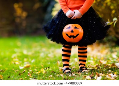 Little Girl In Witch Costume Playing In Autumn Park. Child Having Fun At Halloween Trick Or Treat. Kids Trick Or Treating. Toddler Kid With Jack-o-lantern. Children With Candy Bucket In Fall Forest.