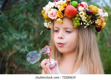 little girl with wreath from flowers blows soap bubbles - Powered by Shutterstock