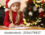 Little girl writing letter to Santa Claus at table indoors, selective focus. Christmas celebration