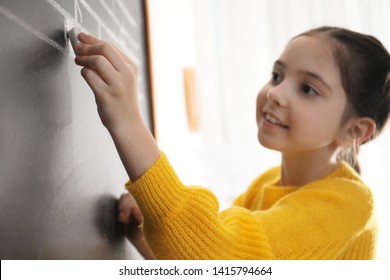 Little Girl Writing Music Notes On Blackboard In Classroom, Closeup