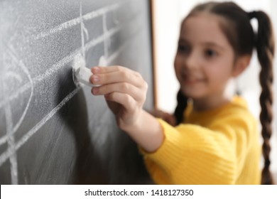 Little Girl Writing Music Notes On Blackboard In Classroom, Closeup