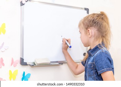 Little girl writing on empty whiteboard with a marker pen