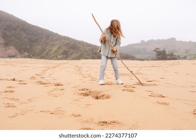 little girl writing on a sand beach with a tree trunk - Powered by Shutterstock