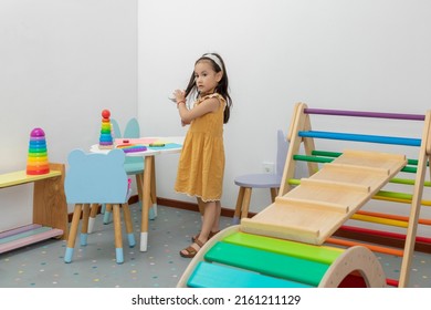 Little Girl In A Yellow Dress Standing In The Recreational Area Of The Pediatric Office