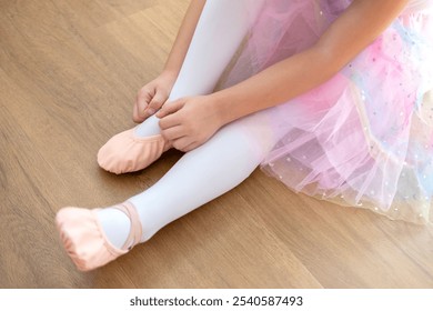 little girl, young ballerina in skirt, Small ballet dancer carefully puts on pink pointe shoes, preparing for ballet performance, dance class - Powered by Shutterstock