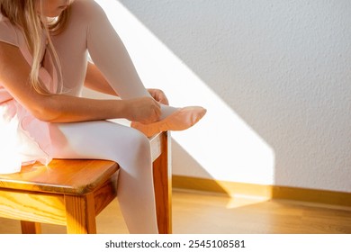 little girl, young ballerina in skirt, Small ballet dancer carefully puts on pink pointe shoes, preparing for ballet performance, dance class - Powered by Shutterstock