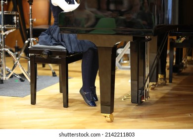 A Little Girl A Young Musician Plays The Piano At A Lesson At School Sitting On A Chair Behind A Musical Instrument Touching The Floor With Her Toe.Concept Photo Music And Creative Development Of Kids