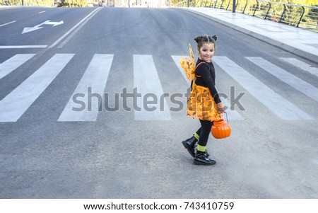 Little girl at zebra crossing in halloween costumes. She is walking towards children party site. Badajoz, Spain