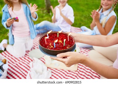 Little girls applauding while woman showing them tasty birthday cake with candles - Powered by Shutterstock