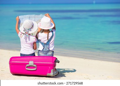 Little girls with big suitcase and map at tropical beach - Powered by Shutterstock