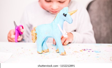 Little Girls Decorating Paper Mache Unicorn With Glitter And Paper Flowers.