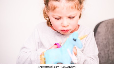 Little Girls Decorating Paper Mache Unicorn With Glitter And Paper Flowers.