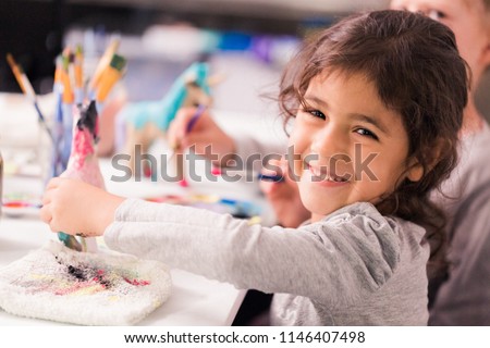 Little girls decorating small paper mache unicorn figurines.