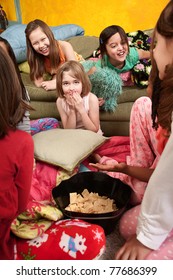 Little Girls Giggle And Eat Snacks At A Sleepover