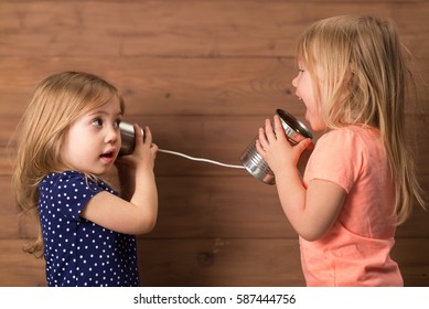 Little girls having fun with tin can telephone