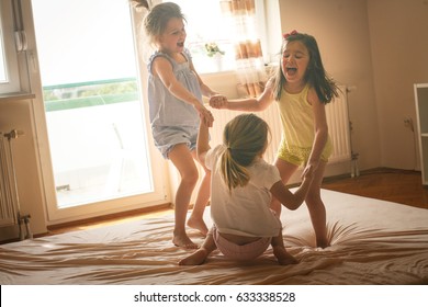 Little girls having fun together in bed. Little girls playing at home on bed. 