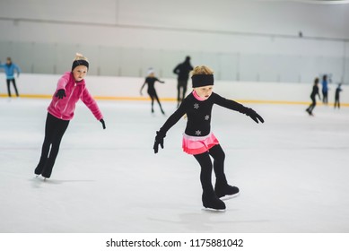 Little Girls Learning To Ice Skate. Figure Skating School. Young Figure Skaters Practicing At Indoor Skating Rink.