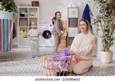 Little Girls Are Playing In The Bathroom, Laundry Room, Dancing, Running While Mom Is Busy Doing Chores, Folding Clothes, Preparing Things To Put In The Washing Machine.