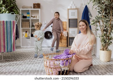 Little Girls Are Playing In The Bathroom, Laundry Room, Dancing, Running While Mom Is Busy Doing Chores, Folding Clothes, Preparing Things To Put In The Washing Machine.