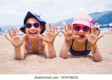 kleine Mädchen, die auf einem Sandstrand spielen und in der Sonne sonnen