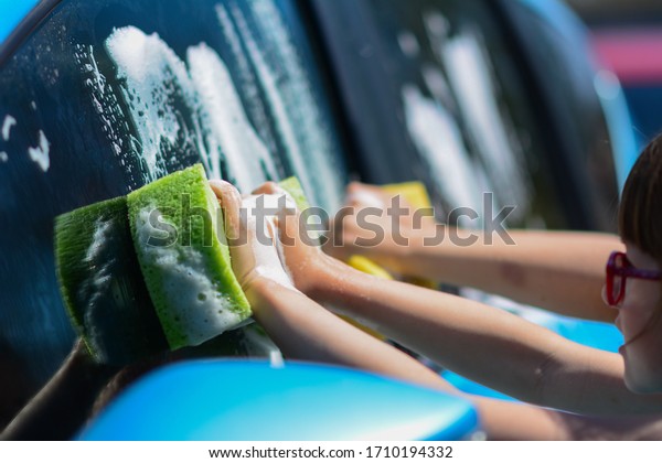 Little girls washing car. Summer.\
Sunset. Closeup side view of a young boy washing car with\
sponge