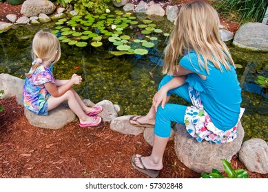 little girls watching koi fish in pond - Powered by Shutterstock