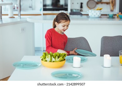 Little Girtl Helping Mother To Set The Table For Dinner, Carrying The Plates, Kitchen Interior, Cropped, Copy Space. Smiling Girl Setting Table.