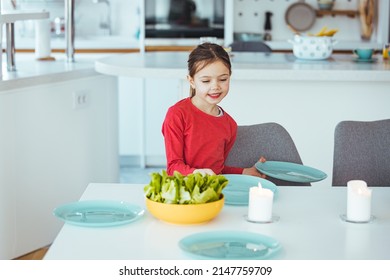 Little Girtl Helping Mother To Set The Table For Dinner, Carrying The Plates, Kitchen Interior, Cropped, Copy Space. Smiling Girl Setting Table.